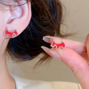 Detail of red Scottish Terrier stud earring with gold-plated trim worn on the earlobe
