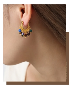 Détail de boucles d'oreilles élégantes en titane doré avec perles d'agate colorées