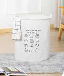 Detail view of white canvas laundry basket with printed clothing icons on a grey rug