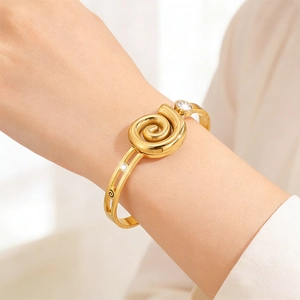 Luxurious 18K gold plated stainless steel open bangle with swirl design and cubic zirconia