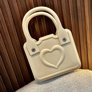 Close-up of cream EVA handbag with embossed heart and silver eyelets on fuzzy rug