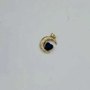 Macro detail of crescent moon pendant with blue heart gemstone and white zircon stones