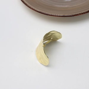 Detailed macro view of golden irregular lava texture hair clip with metallic finish