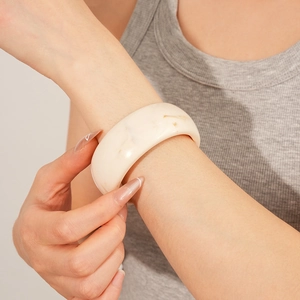 Close-up of cream resin bangle with marble texture on model's wrist for styling view