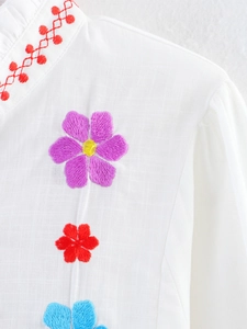Close-up of colorful floral embroidery on a white linen shirt collar and neckline