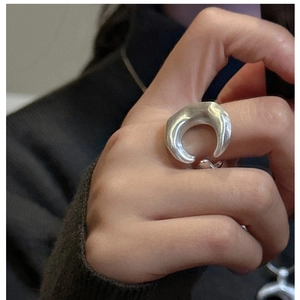 Detail of matte silver minimalist crescent ring on finger with dark knit background