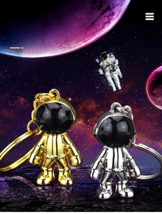 Polished gold and silver astronaut keychains on a space planet surface scene