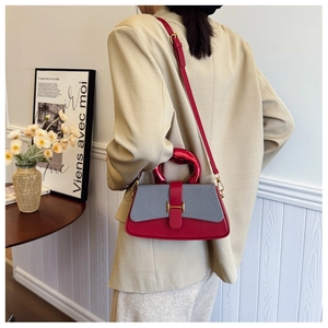Fashionable two-tone handbag with golden H-clasp worn with a beige blazer by a model