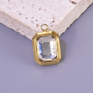 Macro shot of gold plated rectangular charm with a large clear faceted crystal inlay