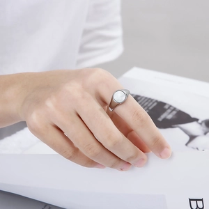 Detail shot of a silver geometric signet ring with a round white inlay worn by a model