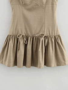 Detail of khaki dress featuring pleated ruffled hem and delicate bow tie ornaments