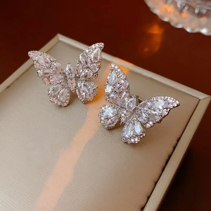 Macro shot of silver butterfly earrings with sparkling cubic zirconia on a beige box