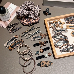 Leopard print hair accessory set with scrunchies and pearl decorated clips on a grey desk