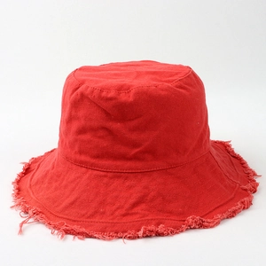 Detailed close-up of a red canvas bucket hat with vintage frayed edges and raw hem textures
