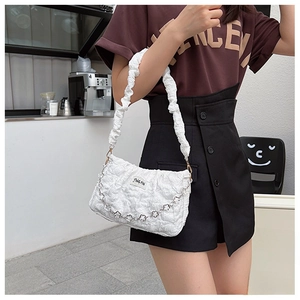 Close-up of white ruched shoulder bag with flower metal chain and textured finish