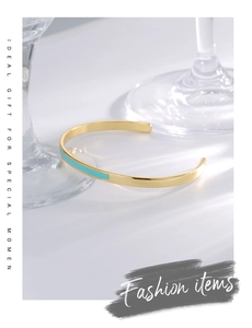 Detail of adjustable gold bangle with sky blue enamel inlay and polished metal finish