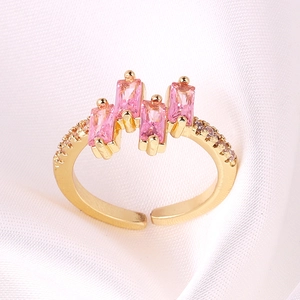 Detailed view of gold plated ring with pink rectangular zircons on white silk background