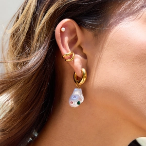 Detailed view of gold hoop earring with baroque pearl and colorful gemstone accents