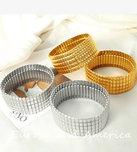 Detail von breiten Stretch-Armbändern mit Karomuster in Gold und Silber auf weißem Stoff