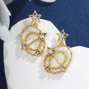 Macro shot of gold geometric earrings with star and circle motifs featuring white zircons