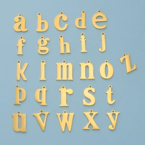 Detailed flat lay of 26 gold lowercase alphabet charms on a blue background