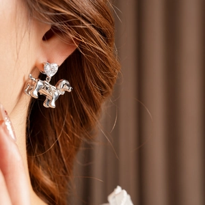 Close-up of silver dog earring with heart stud and crystal inlay on model