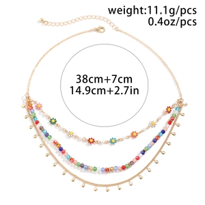 Close-up of bohemian layered gold necklace with colorful beads and daisy charms