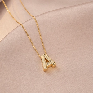 Detail of gold letter A pendant with shimmering zircons on elegant champagne silk