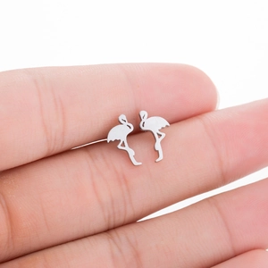 Macro shot of silver flamingo stud earrings on finger showing size and brushed metal texture