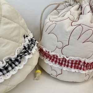Detailed view of quilted cotton drawstring pouches with rabbit embroidery and plaid trim