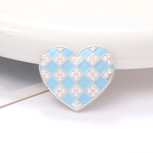 Macro shot of heart-shaped zinc alloy charm with light blue enamel, pearls, and silver trim