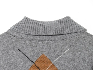 Dettaglio del collo a coste e del classico motivo a rombi su un maglione grigio
