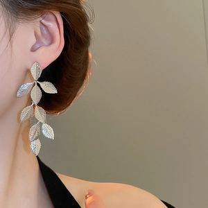 Close-up of silver leaf tassel earrings on a model showing multi-layer metallic details