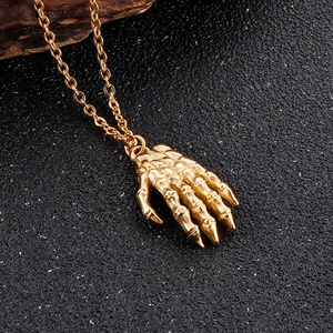 Macro di un ciondolo a mano scheletrica dorata su una catena a maglie in acciaio inossidabile