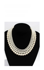 Close-up of elegant multi-layer white pearl necklace displayed on a black velvet mannequin