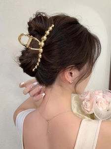 Detail of a large golden beaded hair claw clip worn in a French twist hairstyle