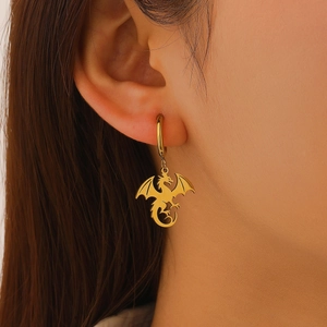 Gros plan d'une boucle d'oreille pendante dragon doré portée sur l'oreille