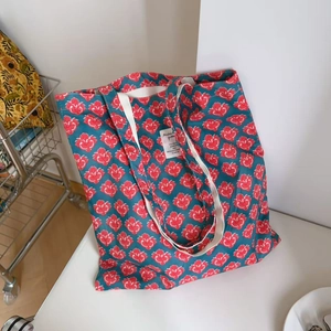 Close-up of vintage Indian print cotton tote bag with red floral patterns and white handle