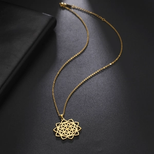 Detail of gold stainless steel necklace with hollow Flower of Life pendant on black background