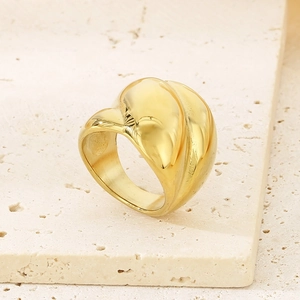 Close-up of 18K gold plated stainless steel twisted ring on a beige stone base