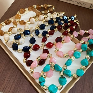Close-up of assorted colorful acrylic beaded necklaces displayed in a gold tray