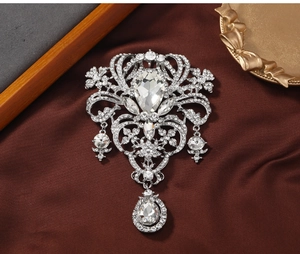 Macro view of vintage silver hollow brooch with radiant rhinestones and pear pendants
