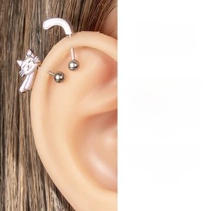 Detailed view of silver cat-shaped ear cartilage piercing on a model ear lobe