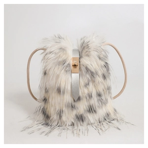 Close-up of white faux fur handbag with black spots and golden turn-lock closure