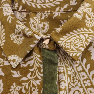 Gros plan détaillé d'un col de chemise en satin avec imprimés floraux et bouton doré