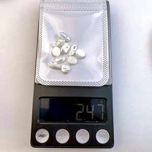 Macro view of 2.47g baroque irregular pearl nail charms on a digital scale