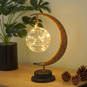 Detail of warm LED copper wire lights inside a glass ball on a crescent moon iron lamp