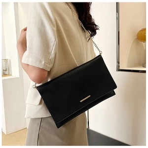Detail of black geometric envelope bag with gold chain and metal bar on the flap