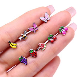 Macro shot of colorful enamel strawberry, grape and banana stud earrings on fingers