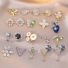 Detailed view of various crystal and pearl brooches on a soft satin background